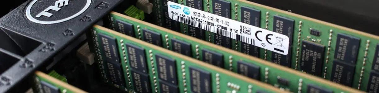 Paměti s zelenými RAM moduly, černými čipy a bílým štítkem v černé zásuvce