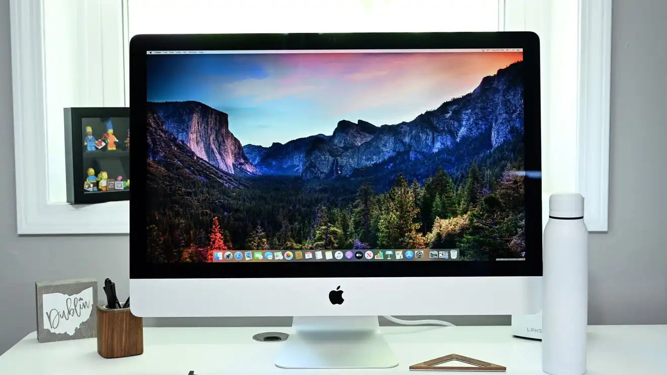 Stříbrný stolní počítač iMac s živou tapetou krajiny.